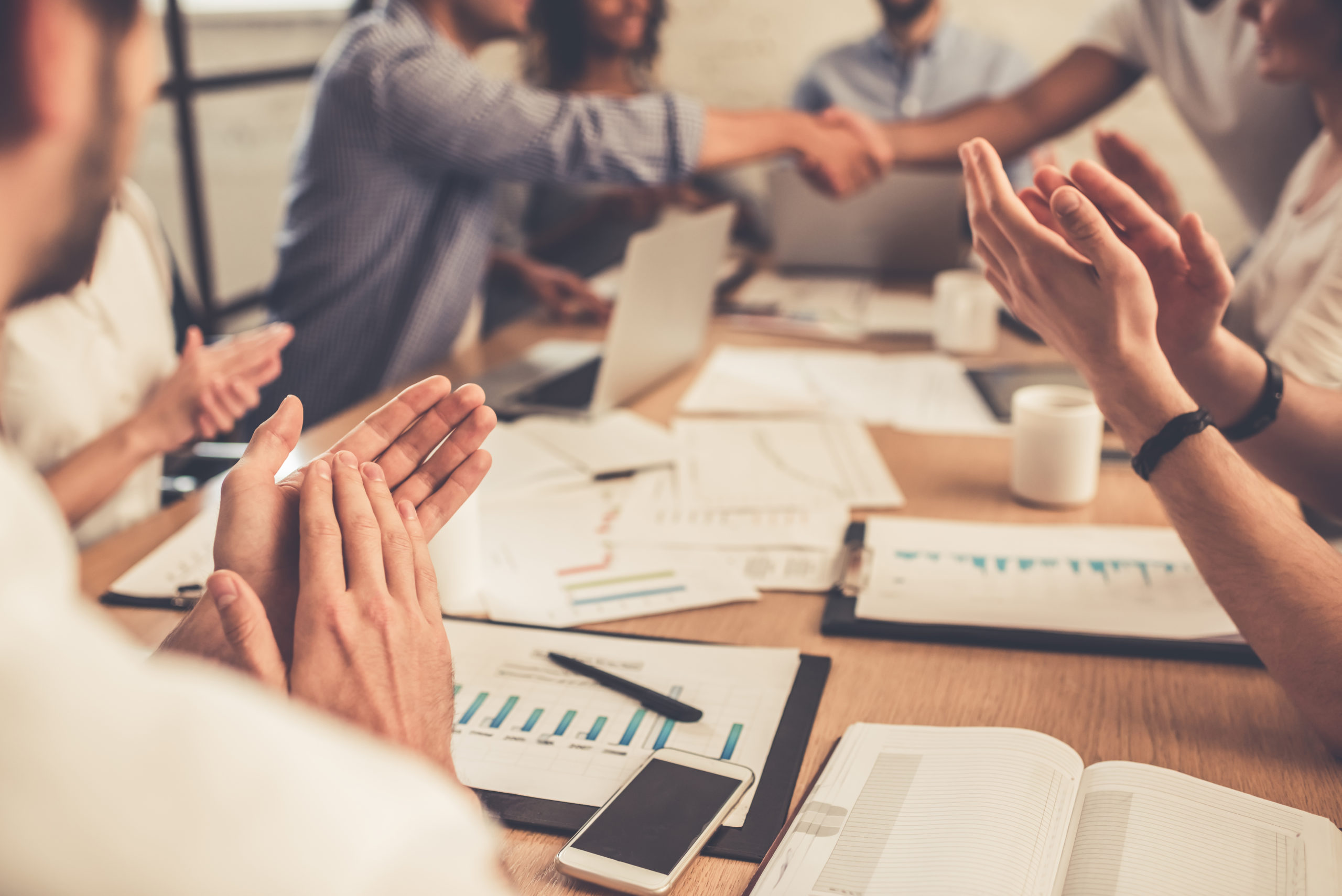 A group of young business people applauding at a conference table